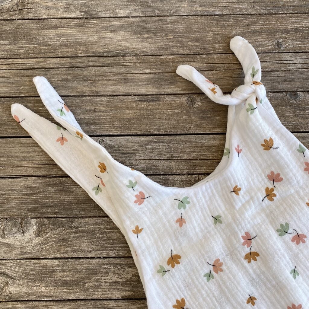 Latzhose, Romper, Einteiler, Strampler, Musselin, weiss mit Blumen, Detail Latz und Knoten