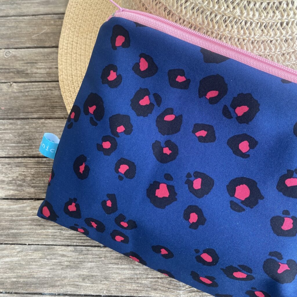Wetbag, Schwimmtasche, Nasstasche aus Softshell für Strand oder Schwimmbad, Leomuster dunkelblau/ pink, Detailaufnahme an Strohhut