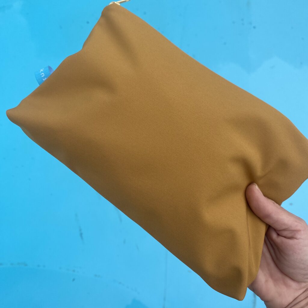 Wetbag, Schwimmtasche, Nasstasche aus Softshell für Strand oder Schwimmbad, Senfgelb, vor Pool