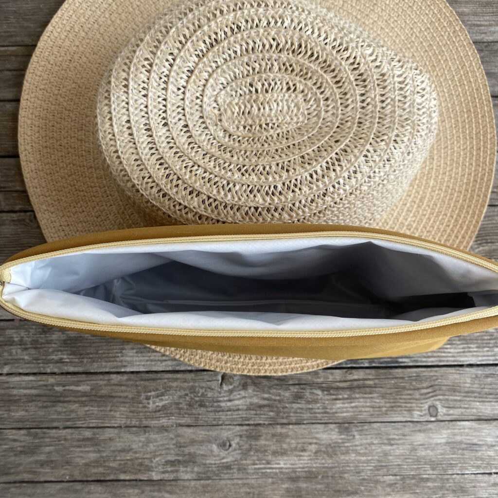 Wetbag, Schwimmtasche, Nasstasche aus Softshell für Strand oder Schwimmbad, Senfgelb, offen und leer an Strohhut