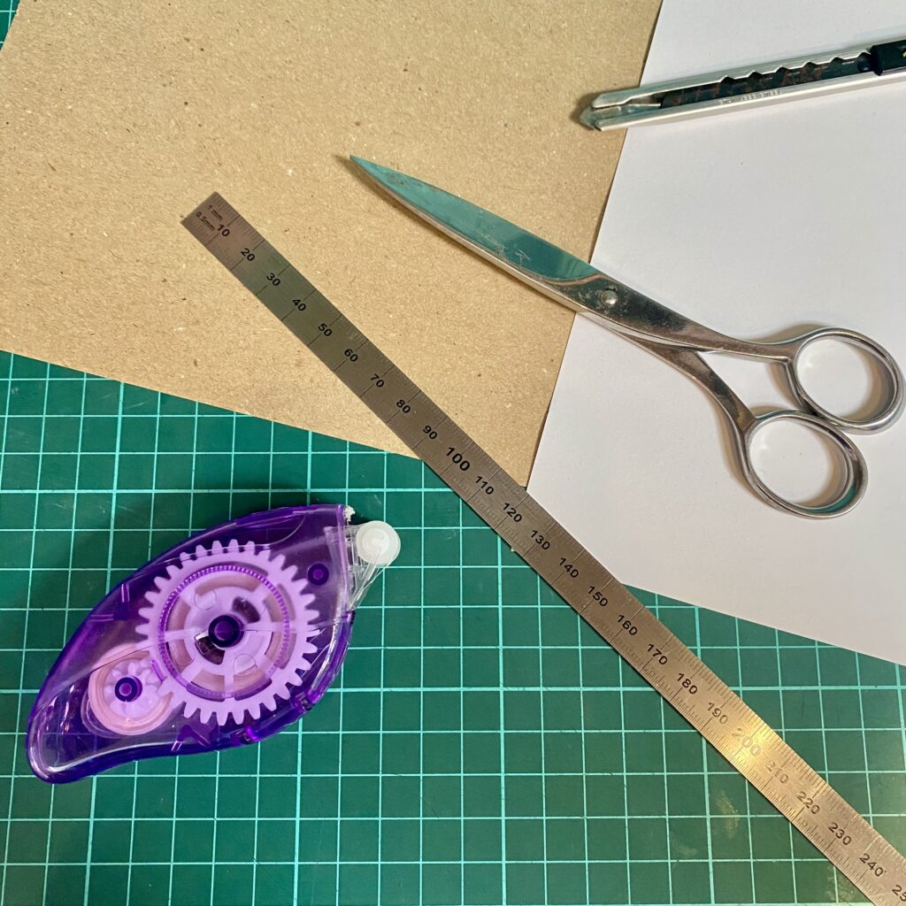 Mein Bastelmaterial - Schere, Metalllineal, Klebemaus, Cutter, weißes Papier, Kraftpapier