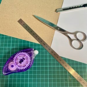 Mein Bastelmaterial - Schere, Metalllineal, Klebemaus, Cutter, weißes Papier, Kraftpapier